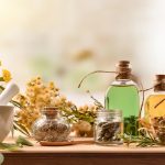 Composition of natural alternative medicine with capsules, essence and plants on wooden table in rustic kitchen. Front view. Horizontal composition.